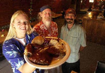 
Erica Schuster, left, holds up a half-chicken barbecue plate which she serves at Gramma's Backyard Barbecue where her dad, Stan 