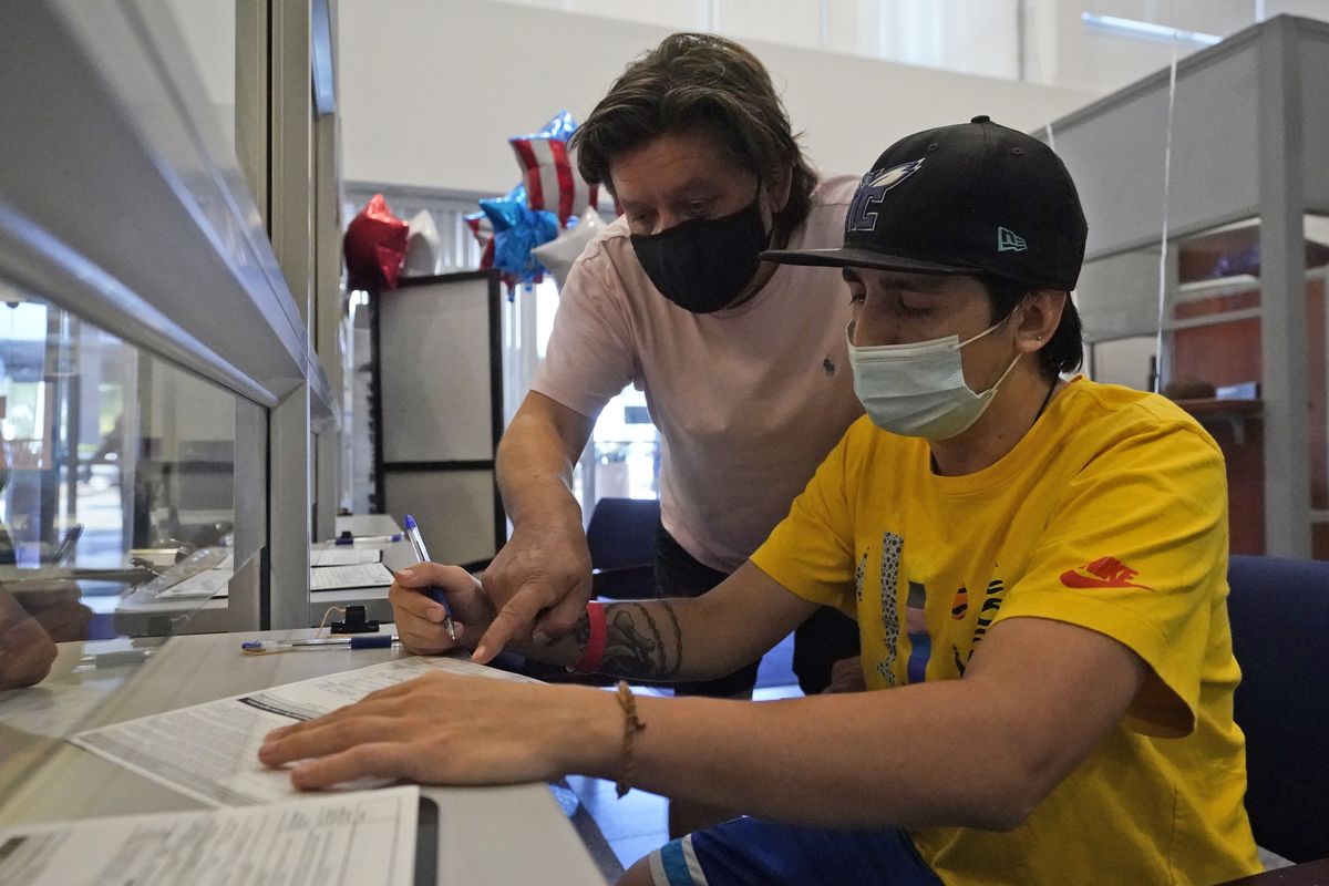 Ramiro Saez, left, helps his son Lucas Saez, 22, fill out a voter registration form, Tuesday, Oct. 6, 2020, at the Miami-Dade County Elections Department in Doral, Fla. Florida Gov. Ron DeSantis extended the state