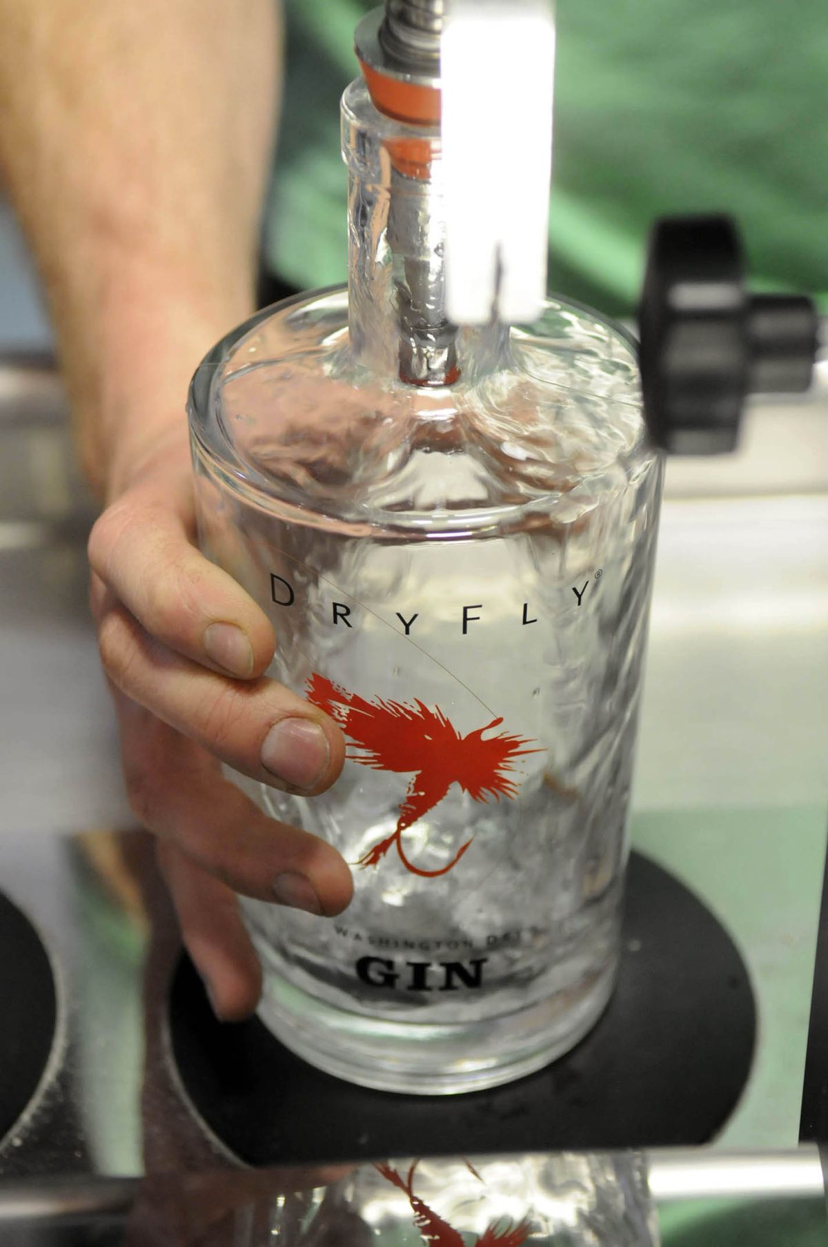 A volunteer places a clean bottle under a spout that fills it with gin Saturday, May 18, 2009, at Dry Fly Distillery in Spokane. The small-batch distiller uses groups of volunteers on Saturdays to bottle their products. (Jesse Tinsley / The Spokesman-Review)