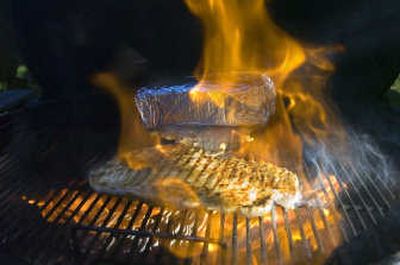 While an already flattened cheicken breast sears on the grill, the other breasts are prepared with an aluminum foil-covered brick laying on top.
(Photo by Christopher Anderson / The Spokesman-Review)