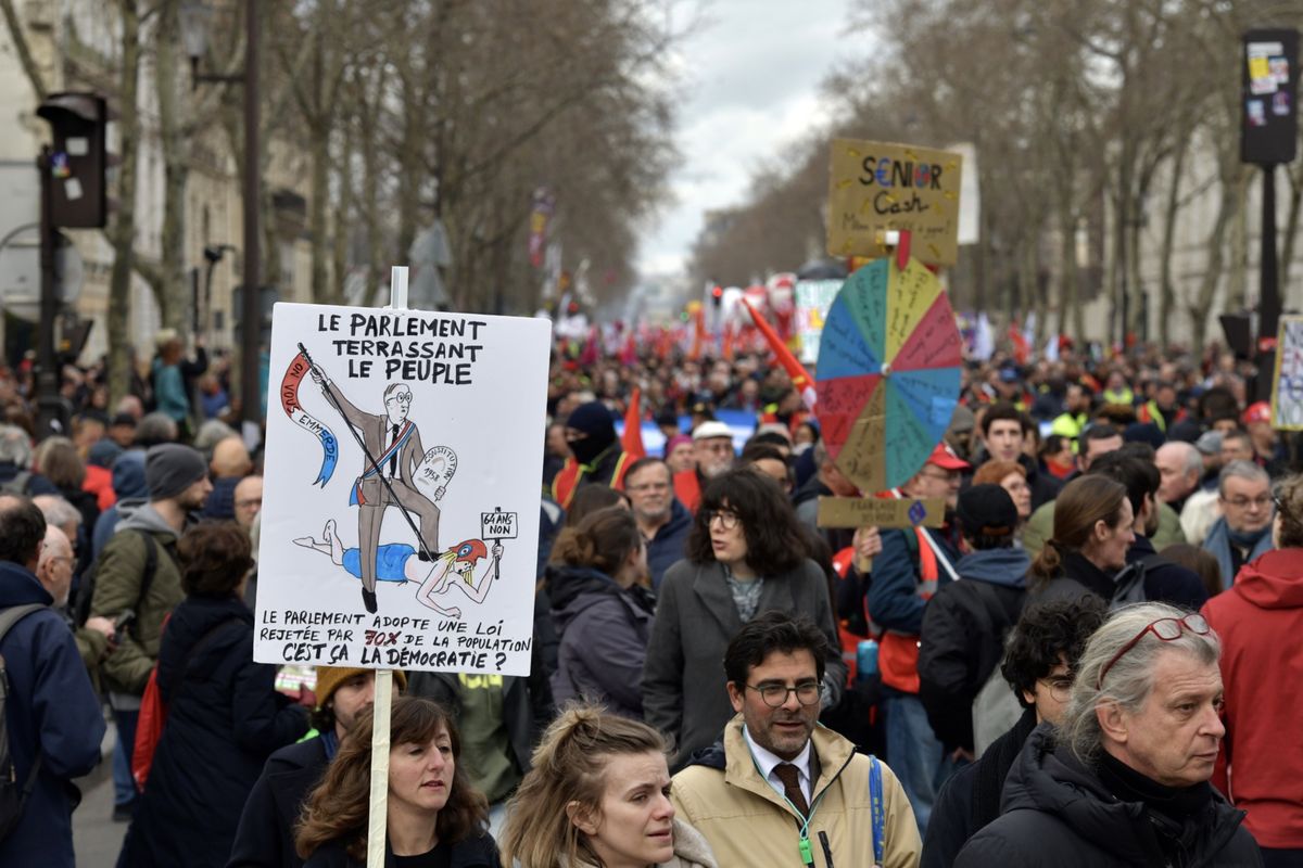 A demonstrator with a placard reading "Parliament Slaying The People" at a protest during a national strike against pension reform, in Paris, France, on Wednesday, March 15, 2023. French unions are holding mass strikes and protests against President Emmanuel Macron