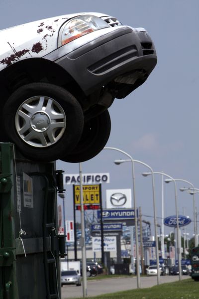 A car protrudes from a waste bin in front of a row of auto dealers in Philadelphia on Monday.  (Associated Press / The Spokesman-Review)