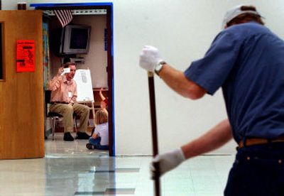 Spencer Normington teaches his first-grade class in the former music room while custodian Duane White cleans the floor of the lunchroom Wednesday at Betty Kiefer Elementary in Rathdrum. A Lakeland School District bond, which could pay for a new elementary school to ease overcrowding, will be voted on Tuesday. 
 (Kathy Plonka / The Spokesman-Review)