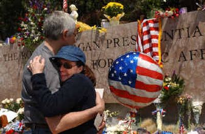 
Julian Caprow hugs his partner, Deborah Evans, as she cries at a makeshift memorial Sunday at the Ronald Reagan Presidential Library in Simi Valley, Calif. 
 (Associated Press photos / The Spokesman-Review)