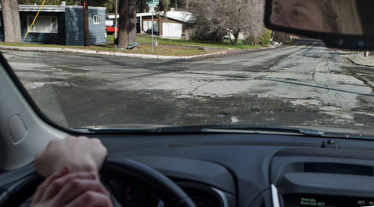 Joy Sheikh drives through the pothole-cracked pavement of her Grandview Thorpe neighborhood in Spokane on Wednesday, March 22, 2017. (Kathy Plonka / The Spokesman-Review)