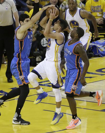 Golden State Warriors guard Stephen Curry, center, shoots between Oklahoma City Thunder center Enes Kanter, left, and guard Dion Waiters during the first half. (Jeff Chiu / Associated Press)