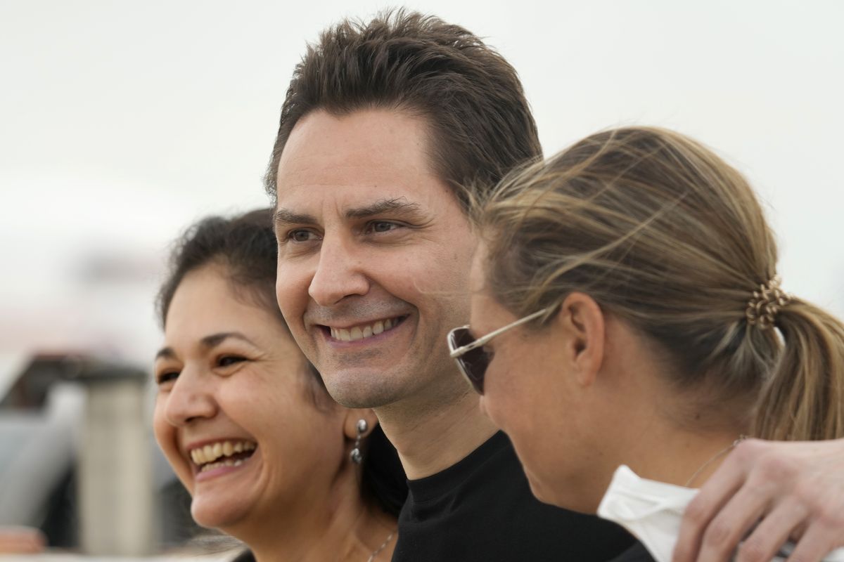 FILE - In this Sept. 25, 2021, file photo, Michael Kovrig, center, embraces his wife Vina Nadjibulla, left, and sister Ariana Botha after arriving at Pearson International Airport in Toronto. Two Canadians, Kovrig and Michael Spavor who were detained in late 2019, days after Huawei’s chief financial officer, Meng Wanzhou, was arrested in Canada at the request of U.S. authorities, have been allowed to return to Canada after being released on bail for health reasons, China