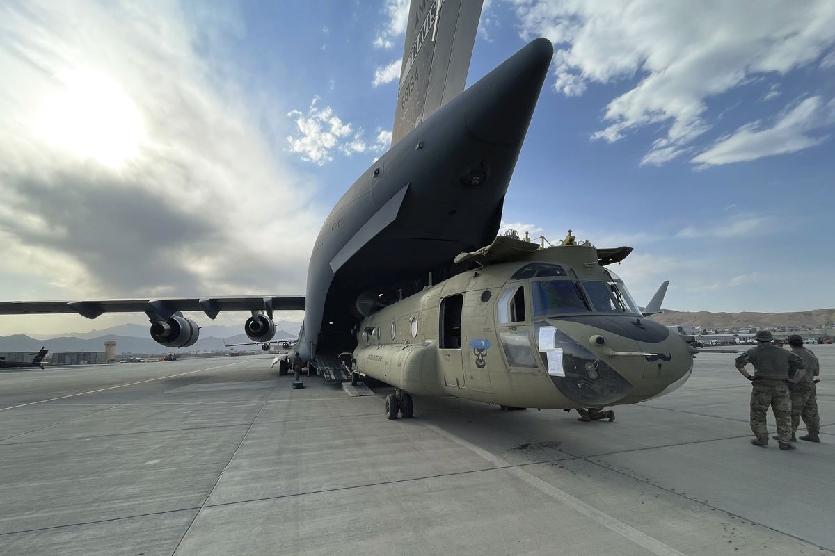 In this image provided by the Department of Defense, a CH-47 Chinook from the 82nd Combat Aviation Brigade, 82nd Airborne Division is loaded onto a U.S. Air Force C-17 Globemaster III at Hamid Karzai International Airport in Kabul, Afghanistan, Saturday, Aug, 28, 2021.  (HOGP)