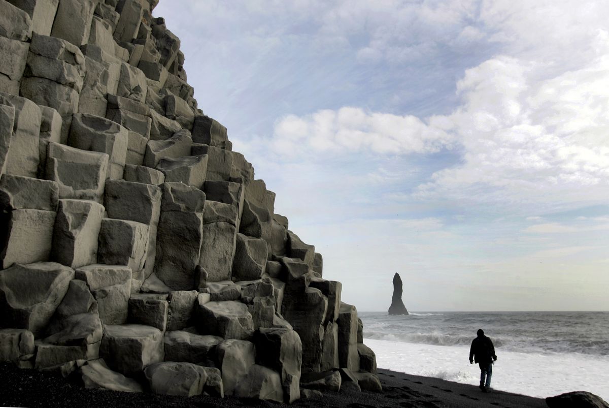 Unusual rock formations tower over a man walking on the black volcanic sands at the beach at Reynishverif, Iceland. Associated Press photos (Associated Press photos / The Spokesman-Review)