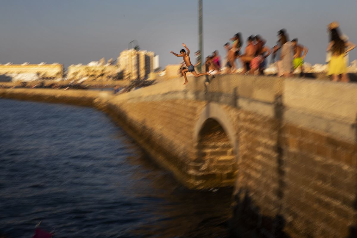 A boy jumps into the water from an ancient bridge leading to the San Sebastian castle in Cadiz, south of Spain, on Friday, July 23, 2020. With the coronavirus rebounding in parts of Spain, it appears that several regions have not adequately prepared to trace new infections in what was supposed to be an early detection system to prevent a new cascade of cases.  (Emilio Morenatti)