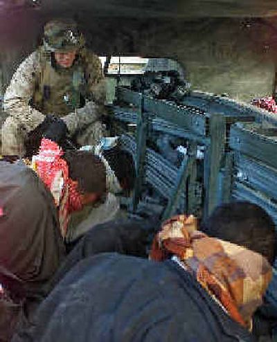
 A U.S. Marine guards prisoners captured Wednesday during a raid in Jabella, Iraq. 
 (Associated Press / The Spokesman-Review)