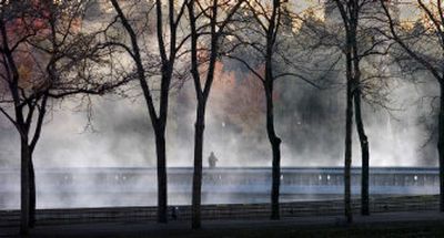 
Fog rises off the Spokane River in Spokane on Wednesday  as the last colors of fall foliage frame a photographer at dawn. 
 (Christopher Anderson / The Spokesman-Review)