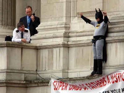 
A police officer, left, watches a protester dressed as Batman, right, who stands on a ledge at London's Buckingham Palace, Monday. 
 (Associated Press / The Spokesman-Review)