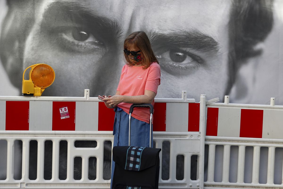 A woman wearing a face mask checks her cellphone downtown in Munich, Germany, Tuesday, Sept. 22, 2020.  (Matthias Schrader)