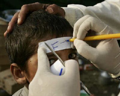 
A doctor writes instructions on the forehead of a boy as he sends him off to a hospital for further treatment on Monday at a medical tent in the town of Bagh, in Pakistani Kashmir.
 (The Spokesman-Review)