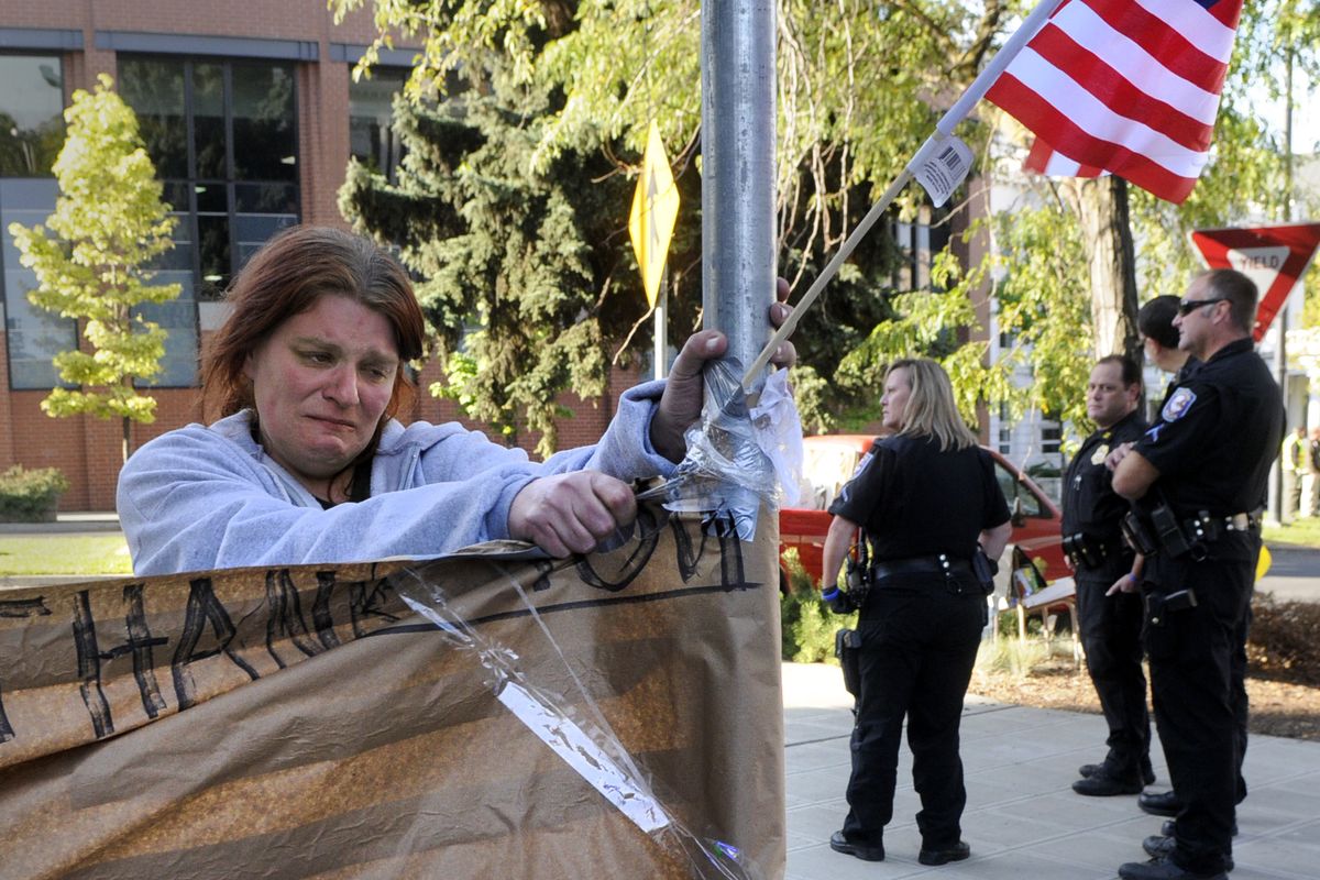 Protester, Jessica McPhail, tearfully tears down signage, ordered by the Spokane Police Department, at the corner of Riverside and Monroe, near the Spokane Club, Sept. 30, 2011, in Spokane, Wash.  A group of protesters have occupied the area for the past three days. (Dan Pelle / The Spokesman-Review)