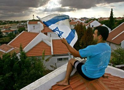 A Jewish settler removes the Israeli flag from the roof of his house Tuesday as he prepares to leave the settlement of Nissanit in the northern Gaza Strip. Nissanit is one of the 21 Jewish settlements in the Gaza Strip that Israel plans to evacuate along with four more in the West Bank starting Aug. 17.
 (Associated Press / The Spokesman-Review)