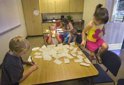 
Sharon Strauss registers her daughter Jailyn, right, for kindergarten Wednesday as her other children play with sticky notes. Jailyn will be joining Kurt, left,  and Zachary,  center,  at Lincoln Heights Elementary while Katelyn, second from right, is still a few years away from starting school. 
 (Christopher Anderson / The Spokesman-Review)