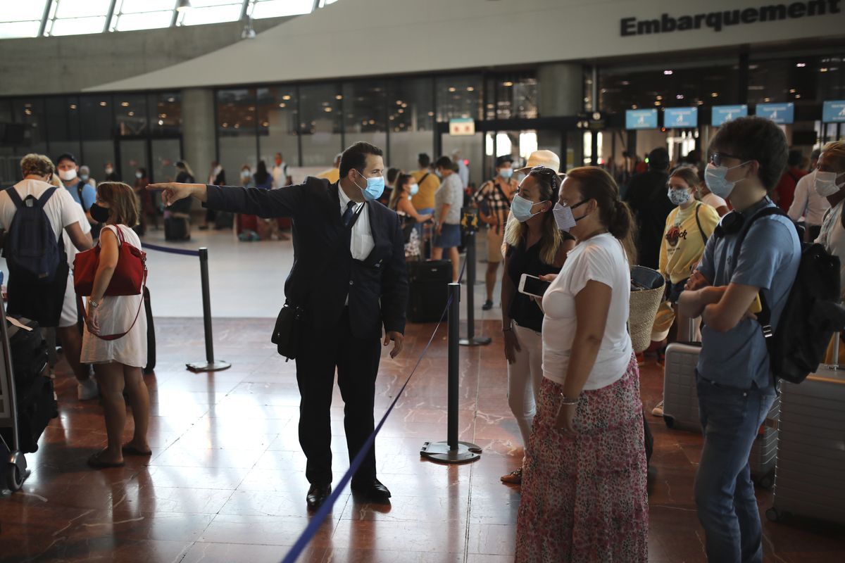 An airport employee directs people for check-in for a British Airways flight to Heathrow airport, Friday Aug.14, 2020 at Nice airport, southern France. British holidaymakers in France were mulling whether to return home early Friday to avoid having to self-isolate for 14 days following the U.K. government’s decision to reimpose quarantine restrictions on France amid a recent uptick in coronavirus infections.  (Daniel Cole)
