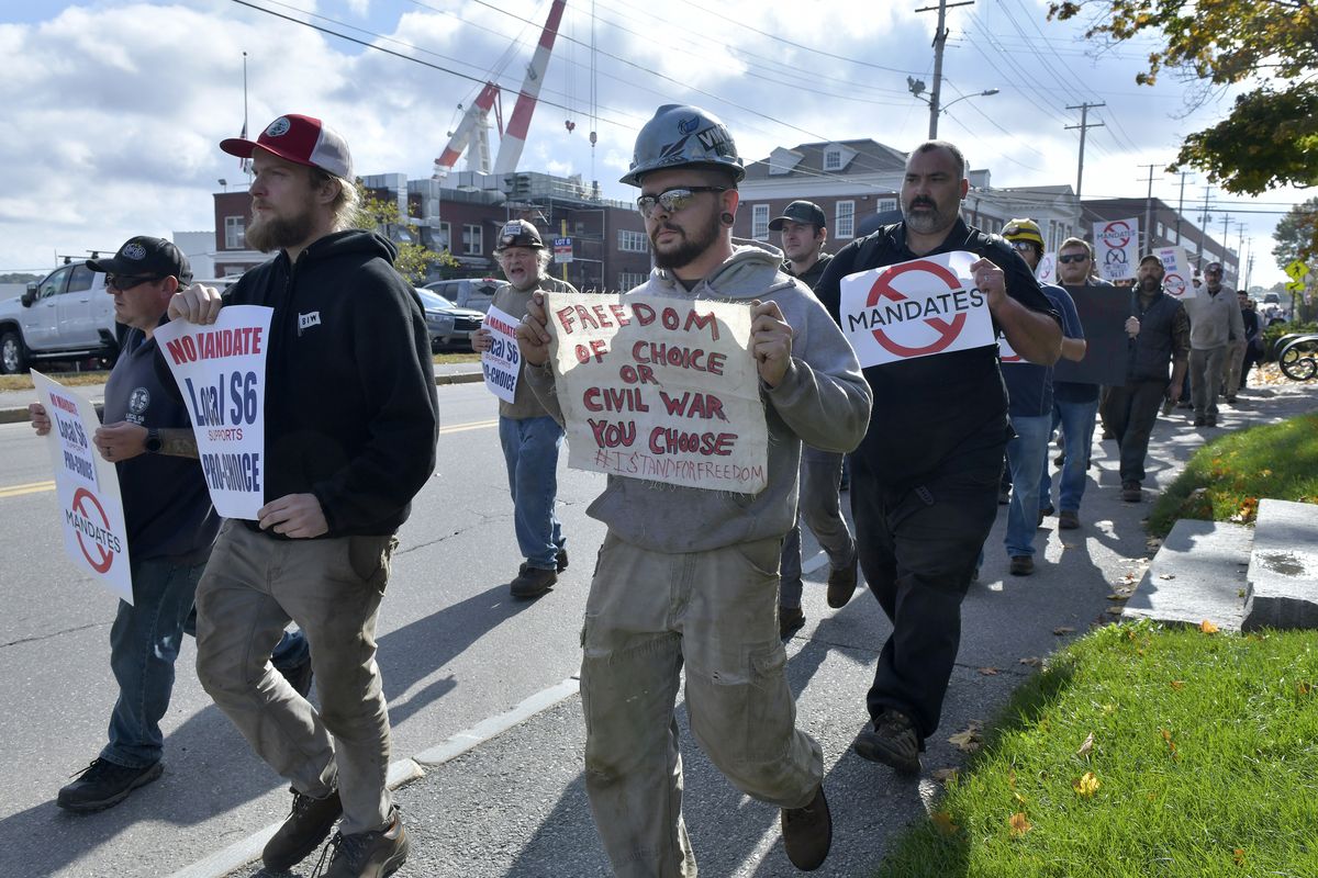 Justin Paetow, center, a tin shop worker at Bath Iron Works, takes part in a demonstration Friday against a COVID-19 vaccine mandate in Bath, Maine.  (Josh Reynolds)