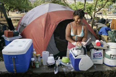 
Surrounded by most of her possessions, a woman who identified herself only as Auntie washes dishes in an ice chest at her campsite on Nanakuli Beach in Waianae, Hawaii. 
 (Associated Press / The Spokesman-Review)