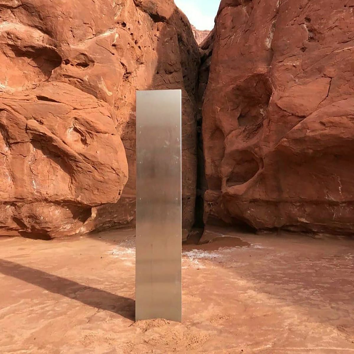 This Nov. 18, 2020 photo provided by the Utah Department of Public Safety shows a metal monolith installed in the ground in a remote area of red rock in Utah. The smooth, tall structure was found during a helicopter survey of bighorn sheep in southeastern Utah, officials said Monday. State workers from the Utah Department of Public Safety and Division of Wildlife Resources spotted the gleaming object from the air and landed nearby to check it out. The exact location is so remote that officials are not revealing it publicly, worried that people might get lost or stranded trying to find it and need to be rescued.  (HOGP)