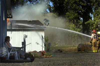 
Wendy Musser, left, talks to the insurance company on the phone as her trailer home burns on Thursday  at 3210 S. Assembly Road. 
 (Jed Conklin / The Spokesman-Review)