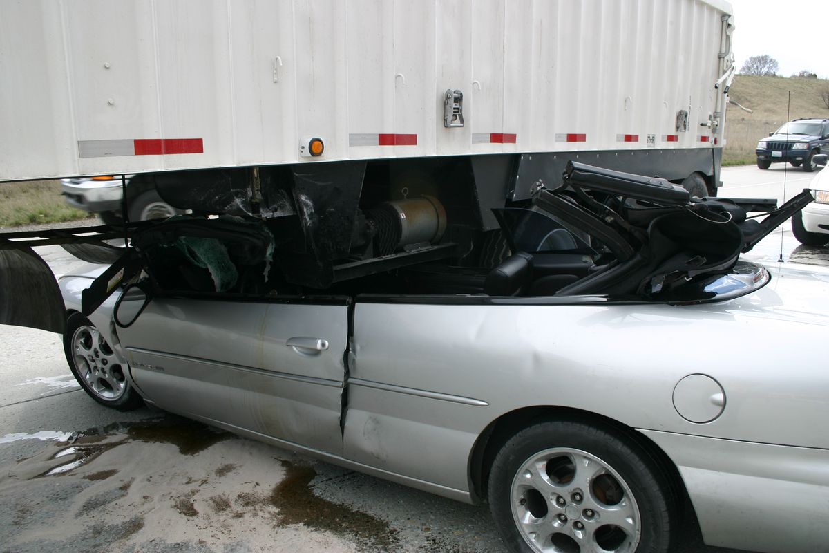 A sedan is wedged below a tractor-trailer on eastbound Interstate 90 on Tuesday, April 6, 2010, in Spokane Valley. The crash sent the car