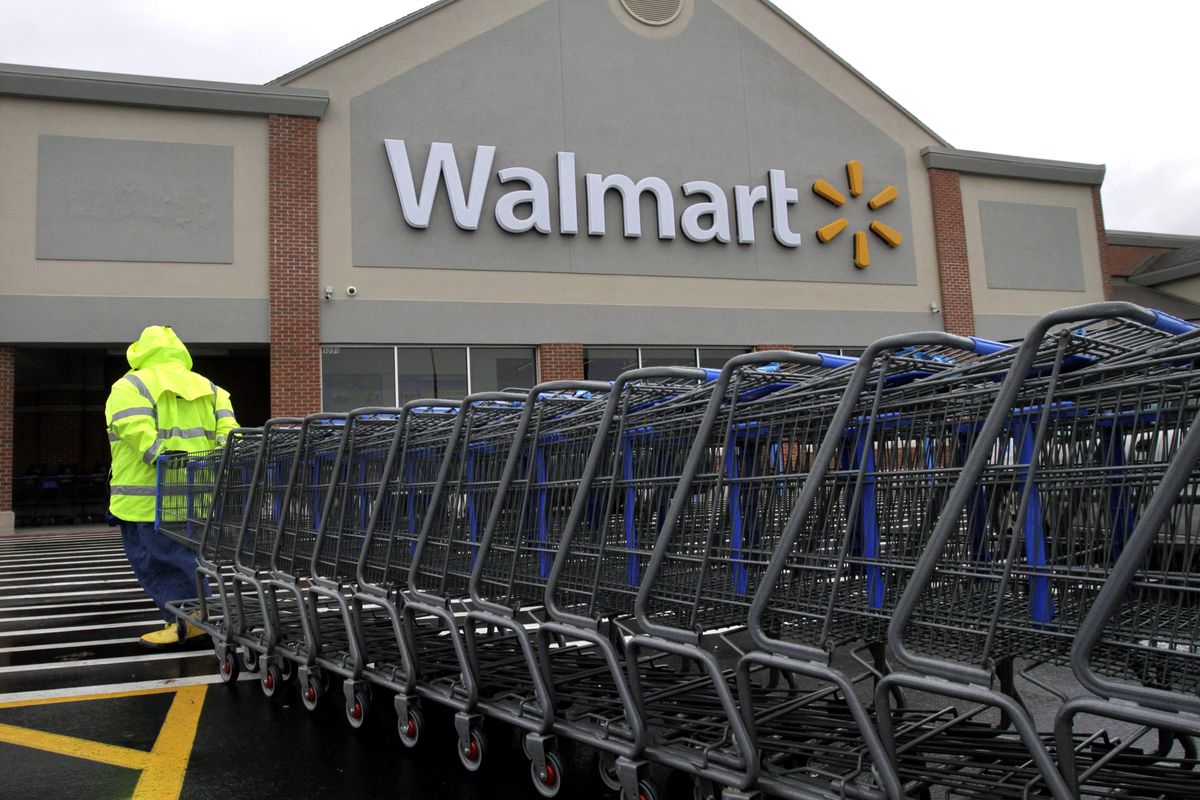 In this Tuesday, Nov. 13, 2012 photo a worker pulls a line of shopping carts toward a Walmart store in North Kingstown, R.I. Wal-Mart Stores Inc. reported a 9 percent increase in net income for the third quarter, but revenue for the world