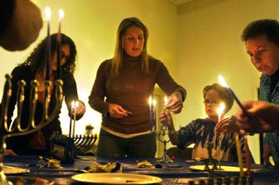 
Rhonda-T Warren and her son Elliott, 9, light the candle representing the second day of Hanukkah on Saturday  in Spokane with Warren's mother, Pam Elkind, and sister Stacey Savatsky. 
 (Jed Conklin / The Spokesman-Review)