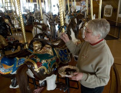 Bette Largent touches up the Looff Carrousel’s horse saddles with brown paint Monday. Largent, a professional carousel horse restoration artist, takes care of the historic Looff Carrousel, which is celebrating its 100th birthday this year.  (Colin Mulvany / The Spokesman-Review)