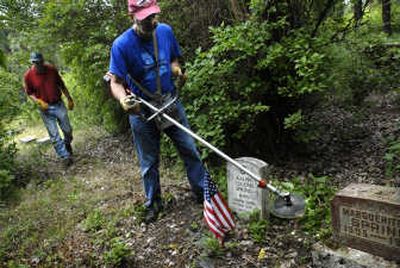 
Stephen Aspinwall, right, and Jerry Cooper  clear overgrown foliage and weeds from headstones at Mica Cemetery on Saturday. 
 (Holly Pickett / The Spokesman-Review)
