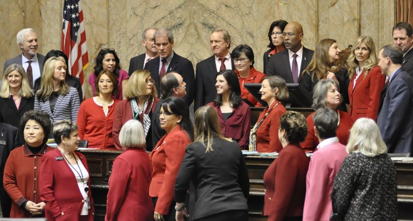 OLYMPIA – Supporters of changes to the Equal Pay Act, many of them dressed in red to mark International Women’s Day, pose for a photo at the House Rostrum after the bill passed Wednesday. (Jim Camden / The Spokesman-Review)