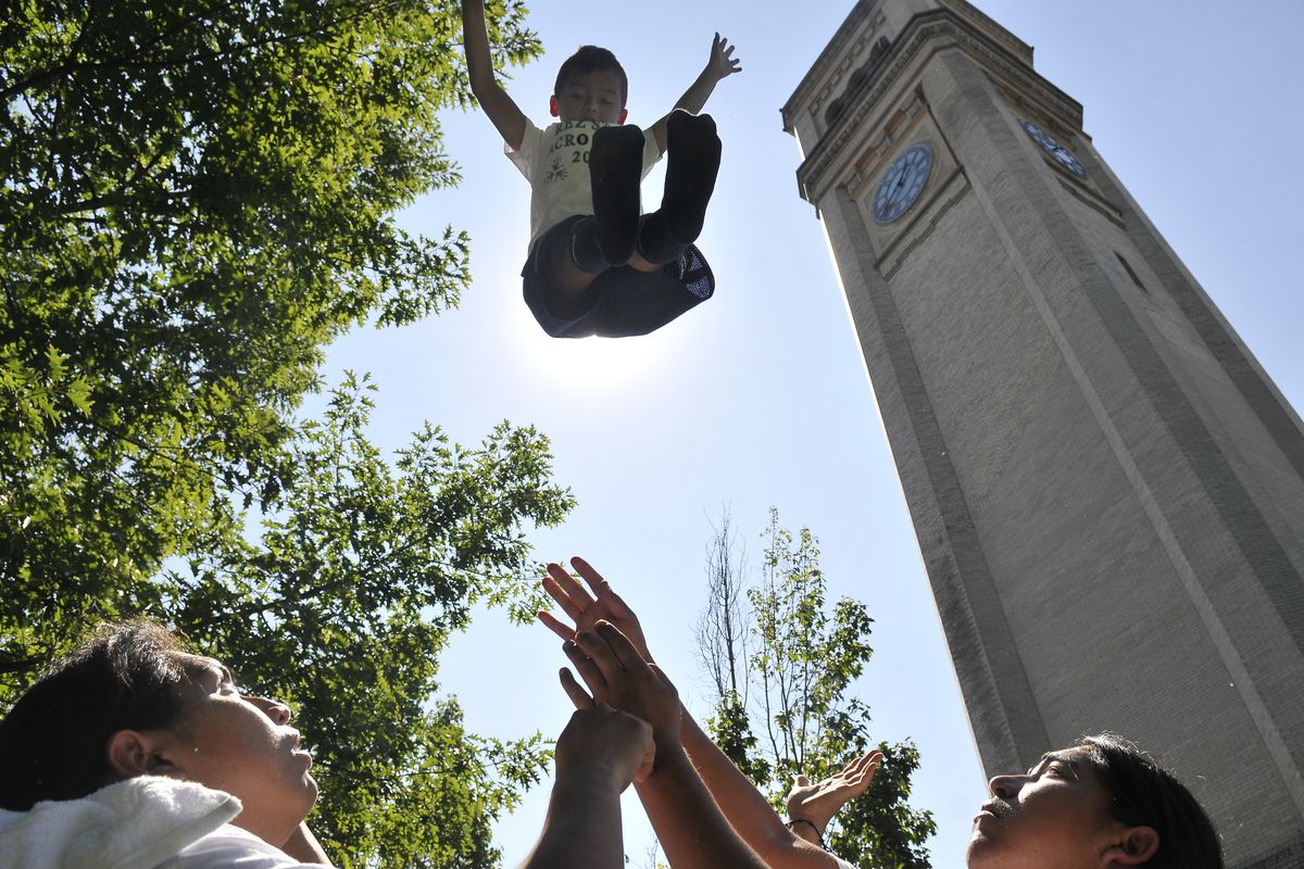 Eight-year-old Dayton Seymour flies skyward after being thrown by Donovan Timentwa, left, and Kelly Watt at Unity in the Community on Saturday. Seymour and other children who took part in an acrobatics camp in Inchelium, Wash., were preparing to show off their new skills. (Jesse Tinsley)