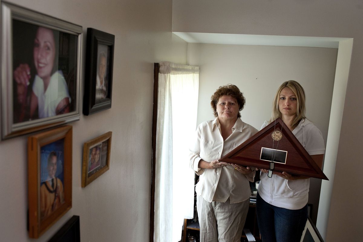Danielle Nienajadlo’s mother, Lindsay Weidman, left, and sister Michelle Scheibner hold the folded flag given to them upon Nienajadlo’s death in 2009. Nienajadlo died from leukemia, which her family believes resulted from exposure to one of the massive “burn pits” in Iraq. (Tyler Tjomsland)