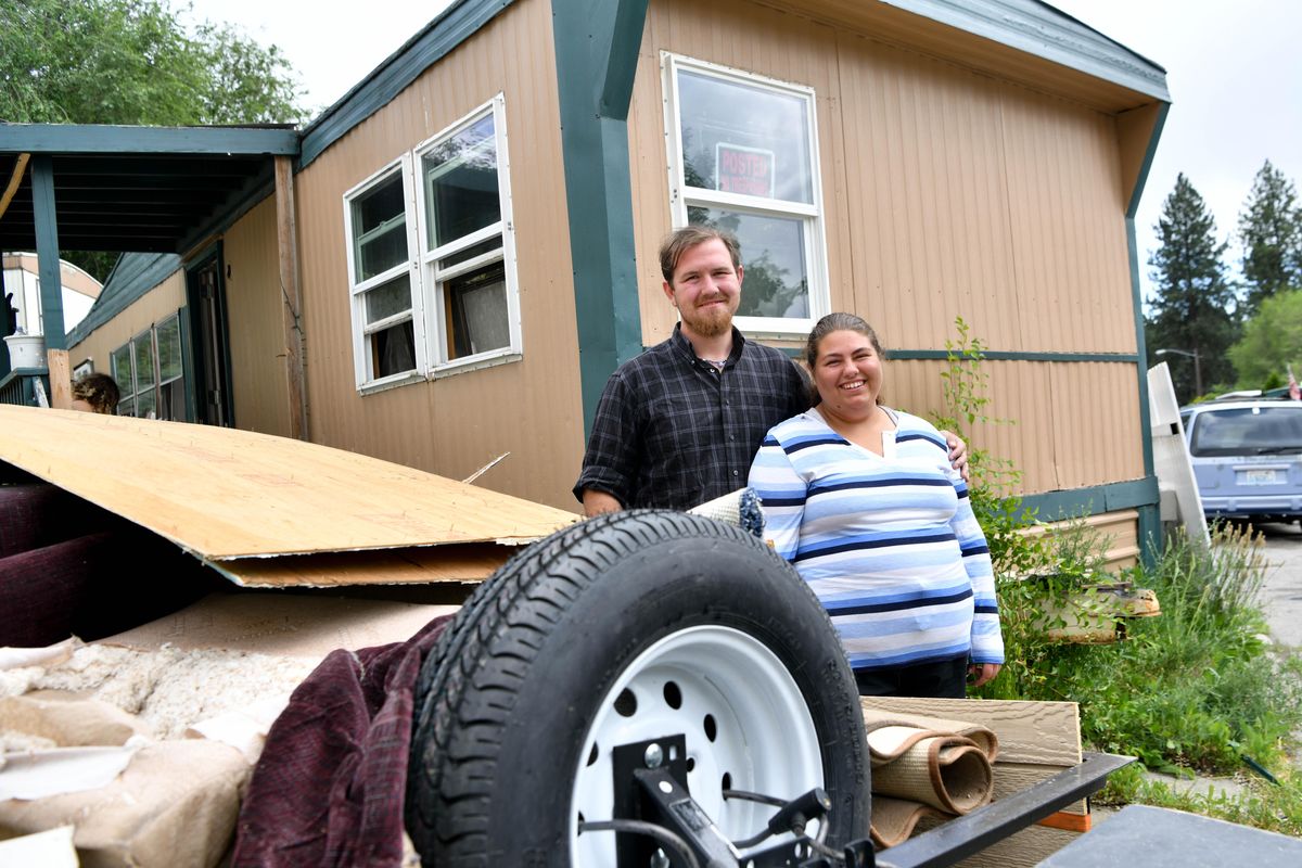 Alexes Wilson, right, and Donaven Farris pose for a photo with their newly acquired mobile home and a trailer full of junk they gutted from it on Wednesday, June 19, 2019, in Spokane Valley, Wash. (Tyler Tjomsland / The Spokesman-Review)