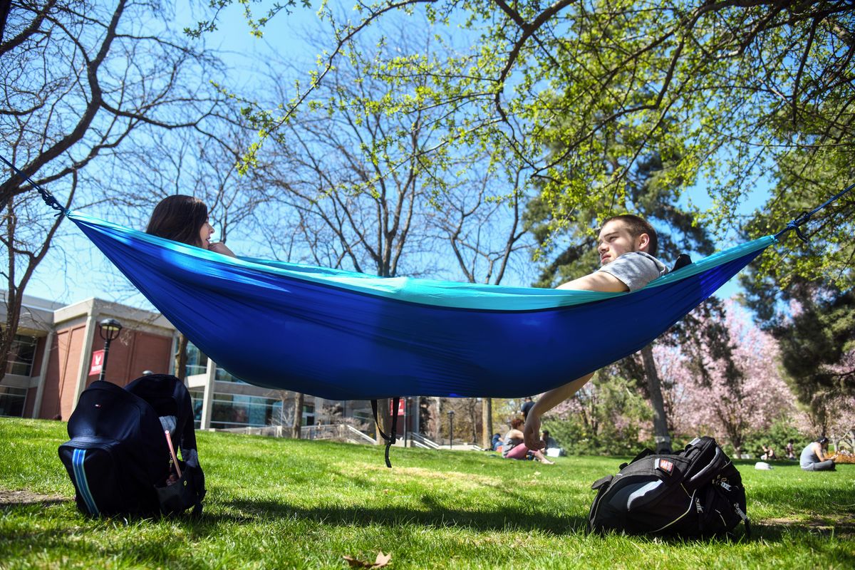 Haley Cardenas, left broke out her hammock for the first time this season and invited Jesse Hannum to swing along during the noon hour, Wednesday, April 25, 2018, on the Eastern Washington University campus. Cardenas says it is a favorite spot because the location is in the shade and not too sunny. Both are from Spokane. (Dan Pelle / The Spokesman-Review)