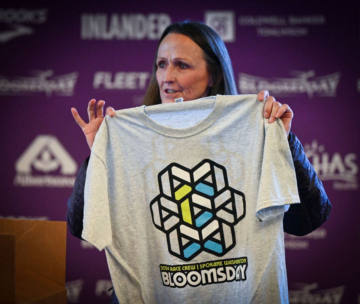 Lilac Bloomsday Association President Dori Whitford reveals the 2024 volunteer T-shirt during a kickoff news conference Thursday at No-Li Brewhouse.  (DAN PELLE/THE SPOKESMAN-REVIEW)