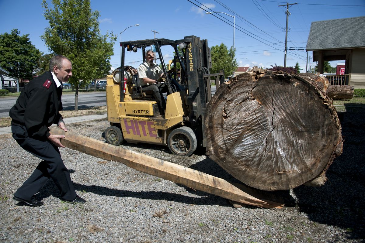Captain Kyle Smith, left, of the Salvation Army, assists Randall Yearout in the unloading of a white spruce tree at the corner of Nora Avenue and Ruby Street in Spokane. The log will be carved into an outrigger canoe by Tiem Clement. (Dan Pelle)