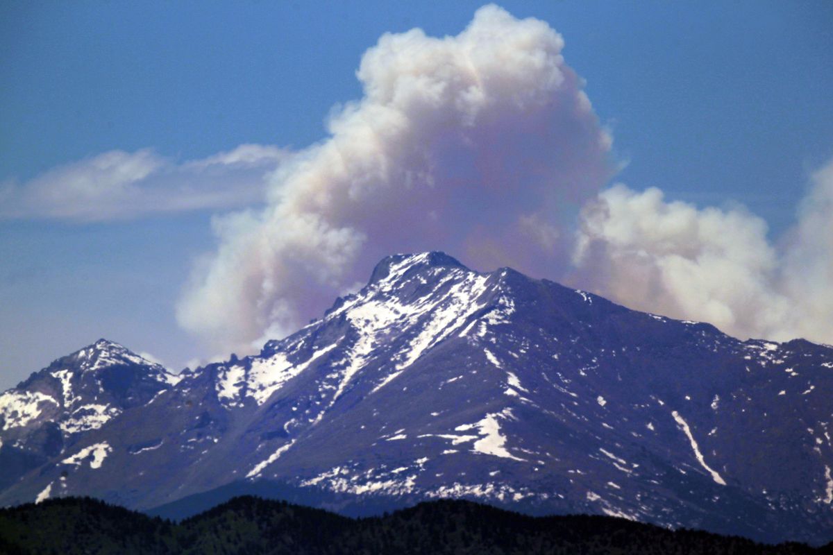 A plume of smoke from the Big Meadows fire in Rocky Mountain National Park rises above Longs Peak, as seen from just east of Boulder, Colo., on June 11. The fire surprised veteran firefighters by marching inexplicably over deep snow. (Associated Press)