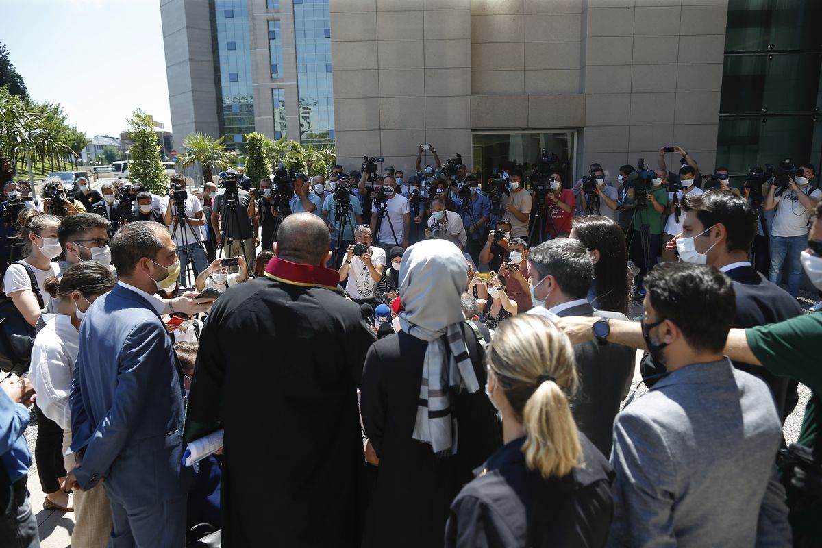 Hatice Cengiz, centre back to camera, the fiancee of slain Saudi journalist Jamal Kashoggi, talks to members of the media outside a court in Istanbul, Friday, July 3, 2020, where the trial in absentia of two former aides of Saudi Crown Prince Mohammed bin Salman and 18 other Saudi nationals over the 2018 killing of the Washington Post columnist had began. Turkish prosecutors have indicted the 20 Saudi nationals over Khashoggi