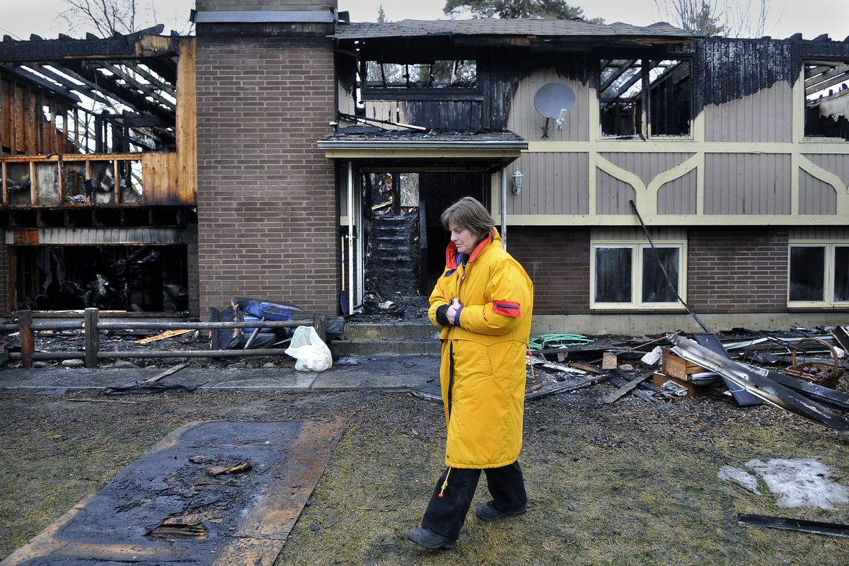 Kayla Stewart walks around her burned-out home on Panorama Road in Spokane County on Monday,  after a fire all but destroyed the house Sunday. After losing most everything to the fire, Stewart was given her mother’s 30-year-old coat to wear. (Dan Pelle)