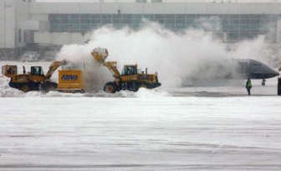 
A United Express regional jet passes behind  crews clearing  fresh snow Tuesday at Denver International Airport.Associated Press
 (Associated Press / The Spokesman-Review)