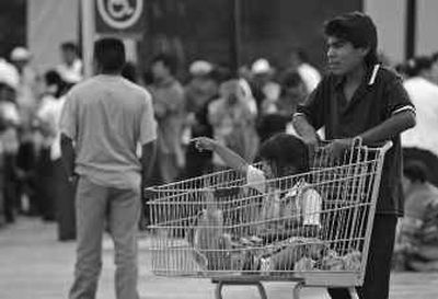
A man and a child on a shopping cart wait for the inaugural opening of the Wal-Mart supermarket near the pyramids in San Juan Teotihuacan, Mexico, on Thursday.
 (Associated Press / The Spokesman-Review)