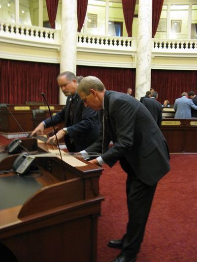 New Idaho Sen. Bob Nonini, R-Coeur d'Alene, a former House member, attaches his nametag to his new desk in the front row of the Senate chamber on Thursday. (Betsy Russell)