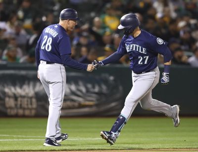 Seattle’s Ryon Healy is congratulated by third-base coach Scott Brosius  after hitting a two-run home run off Oakland’s Mike Fiers  on Friday in Oakland, Calif. (Ben Margot / AP)
