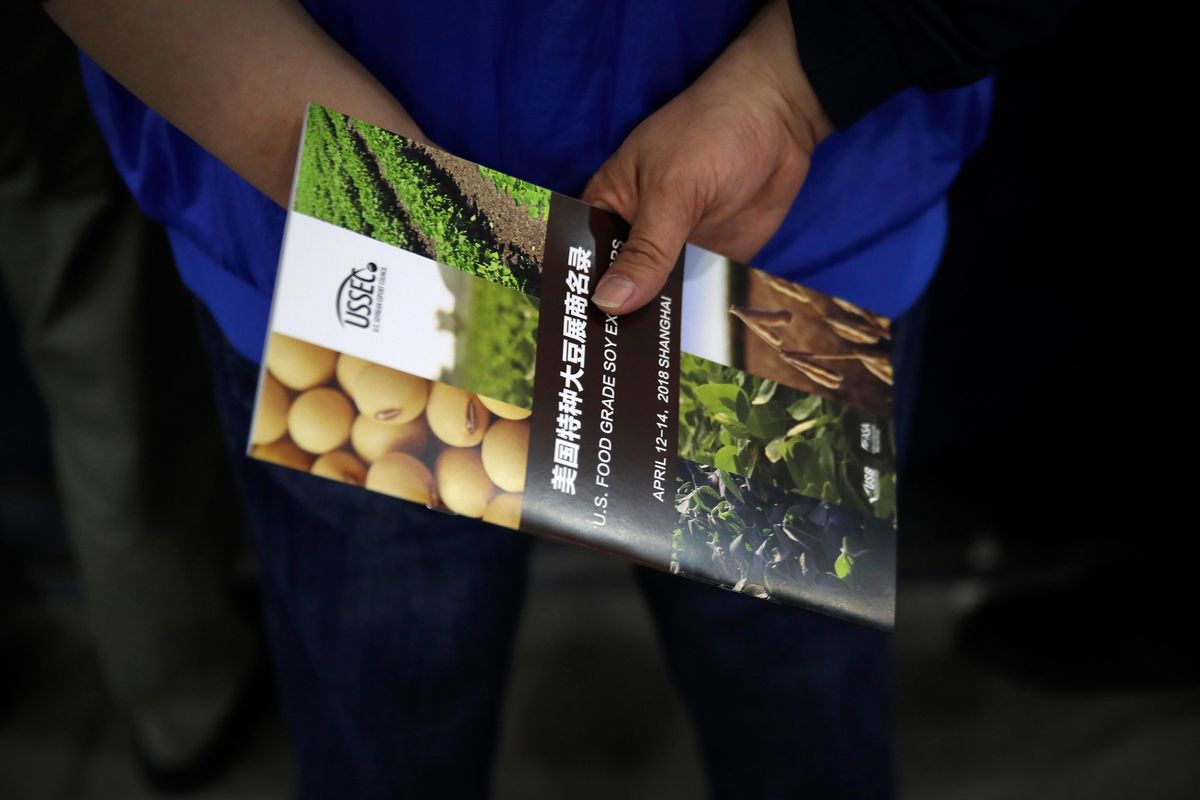 In this Thursday, April 12, 2018 photo, a Chinese visitor holds a U.S. soybean company’s leaflet at the international soybean exhibition in Shanghai. Chinese soybean farmers, importers and processers say they are unconcerned about potential Chinese tariffs on American soybeans in an escalating dispute with the administration of President Donald Trump over trade and technology. (Andy Wong / Associated Press)