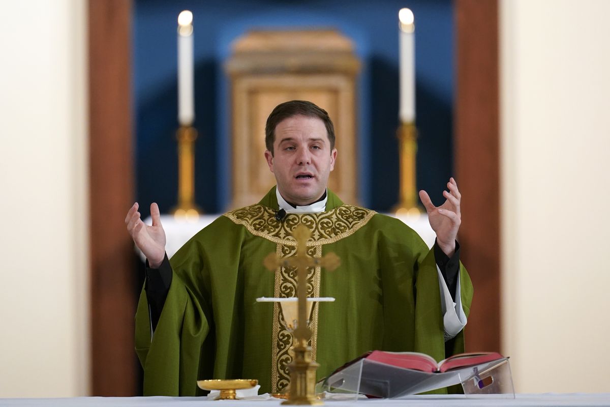 Father Matthew Hood celebrates mass at Our Lady of the Rosary church Friday, Feb. 18, 2022, in Detroit. In 2020, one word caught the ear of a young Detroit-area Catholic priest while he watched a video of his baptism from decades earlier. "Wait," the Rev. Matthew Hood recalled thinking. "Something doesn