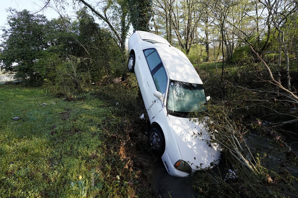 A car that was carried by floodwaters leans against a tree in a creek Sunday, March 28, 2021, in Nashville, Tenn. Heavy rain across Tennessee flooded homes and roads as a line of severe storms crossed the state.  (Mark Humphrey)