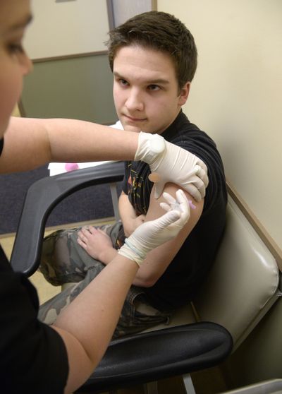 Darlene Kittilstved, a registered nurse at the Chas Market Street Clinic, gives Jake Boles, 15, a flu shot Thursday. At least two people have died in Spokane hospitals from the flu this season. (Colin Mulvany)